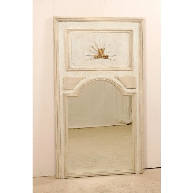 A tall French painted wood trumeau mirror from the 19th century. This antique mirror from France features the tall...