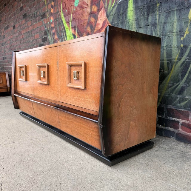 This is a nine drawer dresser in the style of James Mont. It features 3 large drawers on the bottom and 2 smaller drawers...