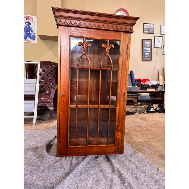 This display cabinet features classic mahogany construction with distinct Gothic-inspired glazing bars, a style popular in...