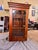 This display cabinet features classic mahogany construction with distinct Gothic-inspired glazing bars, a style popular in...
