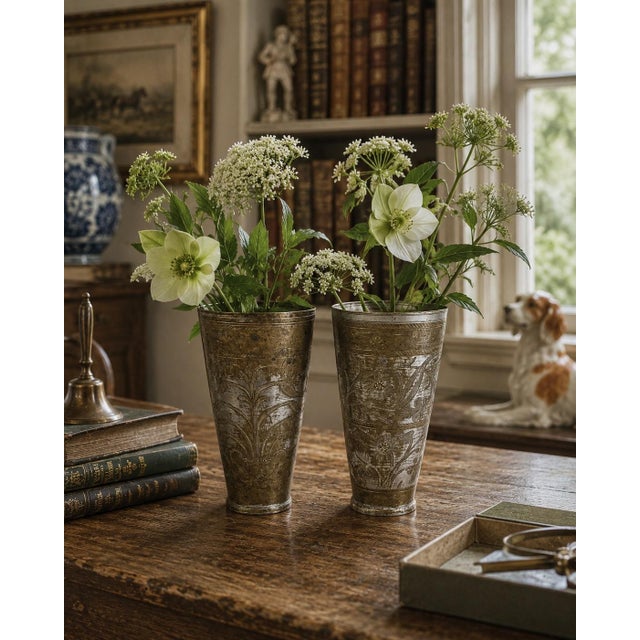 A characterful pair of early 20th-century Indian lassi cups, individually hand engraved with scrolling flowers, leafy...