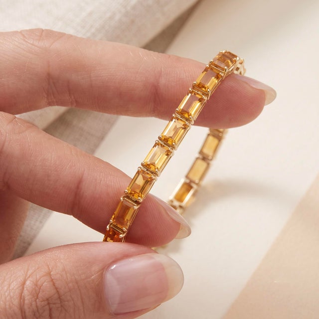 Elevate your everyday look with this elegant, light-catching tennis bracelet featuring a seamless row of warm, golden...