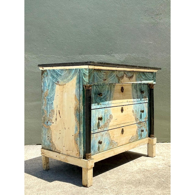 Exuding grand Neoclassical proportions and a captivating aged patina, this vintage commode makes a dramatic artistic...