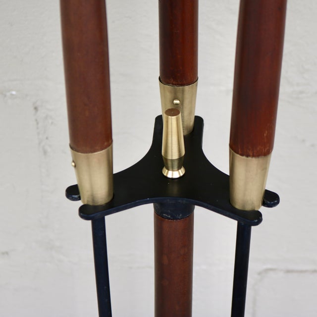 Four piece set of mid-century modern fireplace tools. Features wrought iron frame and tools with wooden handles and brass...