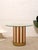 A playful statement dining table with a bold cylindrical pedestal wrapped in alternating burnt orange and cream stripes....