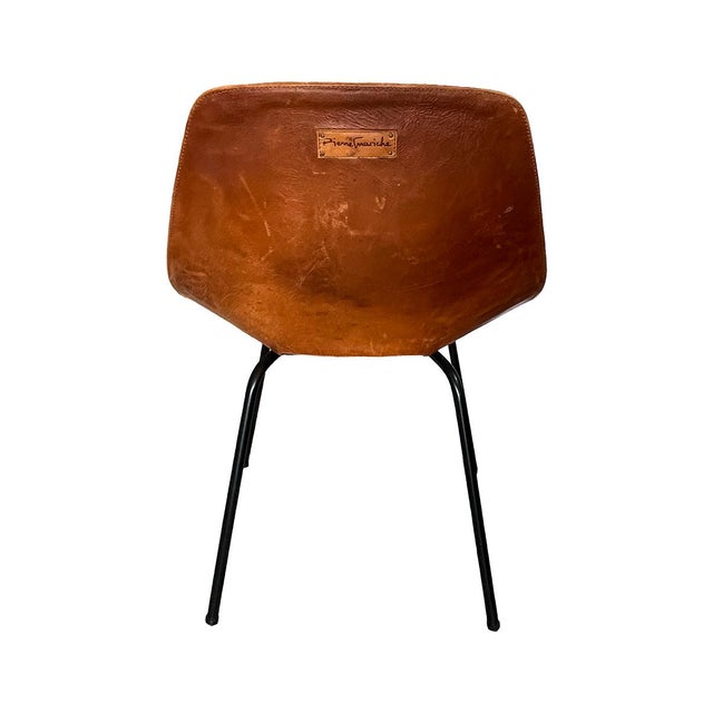 This Tonneau Chair is designed and signed by Pierre Guariche. Manufactured by Siege Steiner in France, featuring cognac...