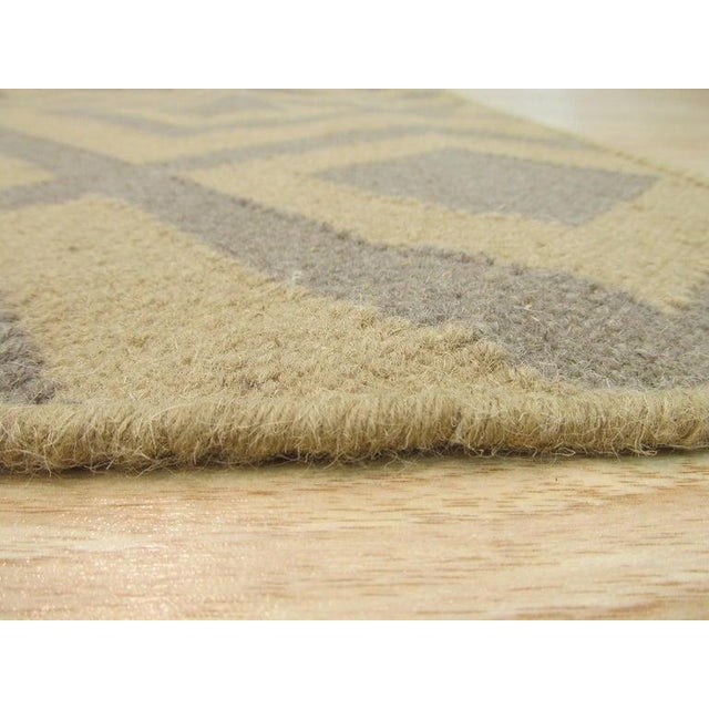 This handmade wool rug features a flat weave construction in a neutral palette of ivory, beige, cream, and white. As a...