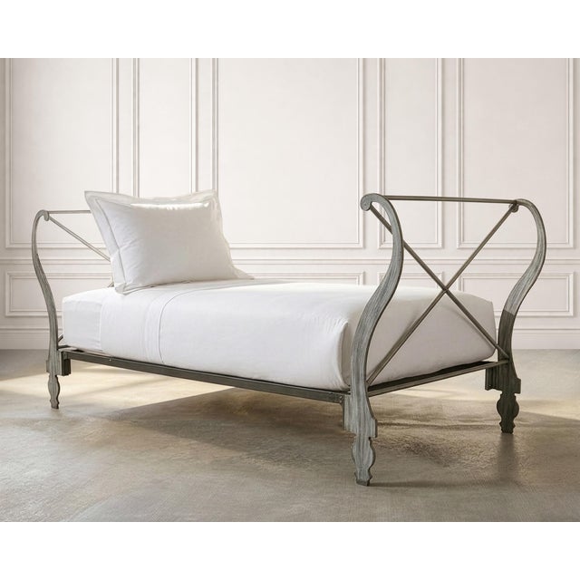 An elegant and whimsical 20th century painted iron daybed crafted in a French Neoclassical Directoire style. The piece is...