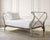 An elegant and whimsical 20th century painted iron daybed crafted in a French Neoclassical Directoire style. The piece is...
