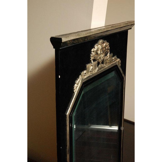 Art Deco wall mirror in black lacquer with white gold-leaf details. Ornate floral carving decorating top of mirror....