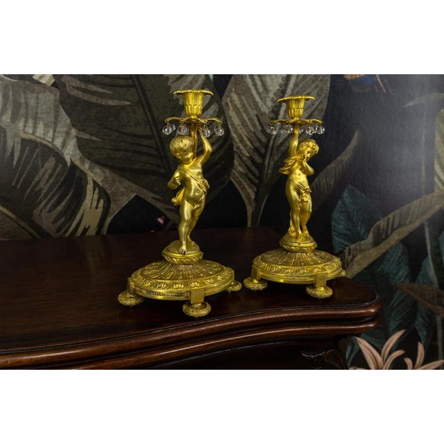 Pair of French Neoclassical cherub candleholders, late 19th century. Elegant candleholders featuring finely modeled bronze...
