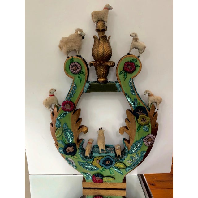 A charming imaginative sculpture created on a vintage carved wood fragment in the shape of a lyre, intricately adorned...