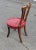 Single side chair with round red seat with brass handle on top.