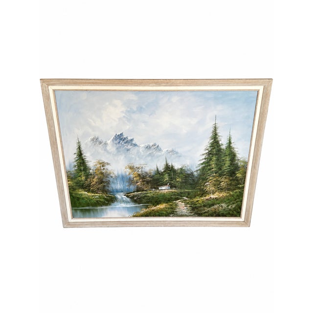 An atmospheric mountain landscape depicting snow-capped peaks rising beyond a lush evergreen forest. A small pale cabin...