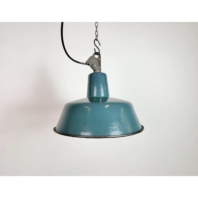 Industrial green (petrol) enamel pendant light made by Polam Wilkasy in Poland during the 1960s. White enamel inside the...