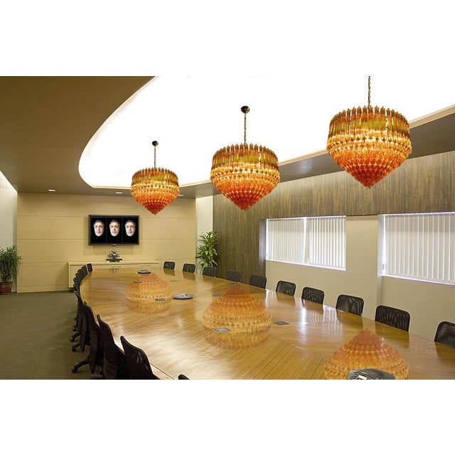 A magnificent Pair Murano glass chandeliers, 265 amber quadriedri on gold frame. This large midcentury Italian chandelier...