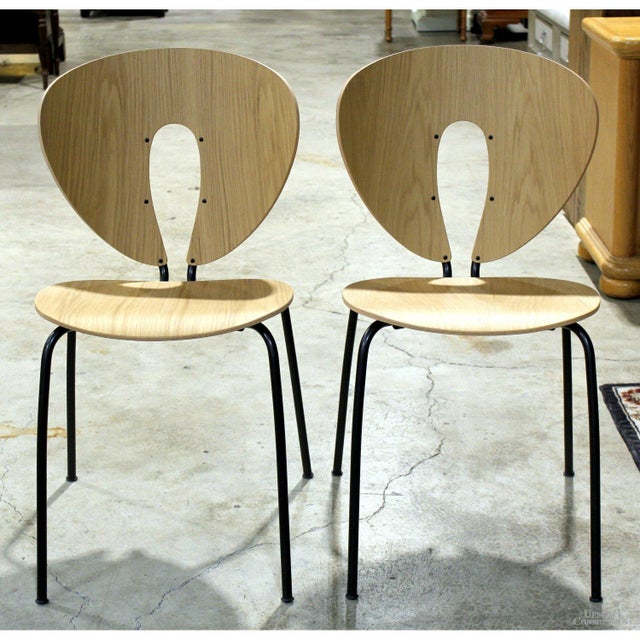 The chairs feature sculpted oak seats and backrests with a distinctive teardrop cutout that adds visual lightness to the...