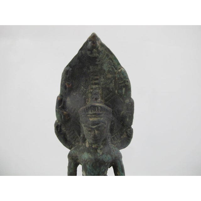 Antique Bayon style Khmer bronze figurine depicting the Buddha sheltered by the Naga serpent king Muchalinda. The Buddha...