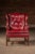Classic wingback lounge chair upholstered in richly patinated red leather with a deeply button-tufted back, rolled arms,...