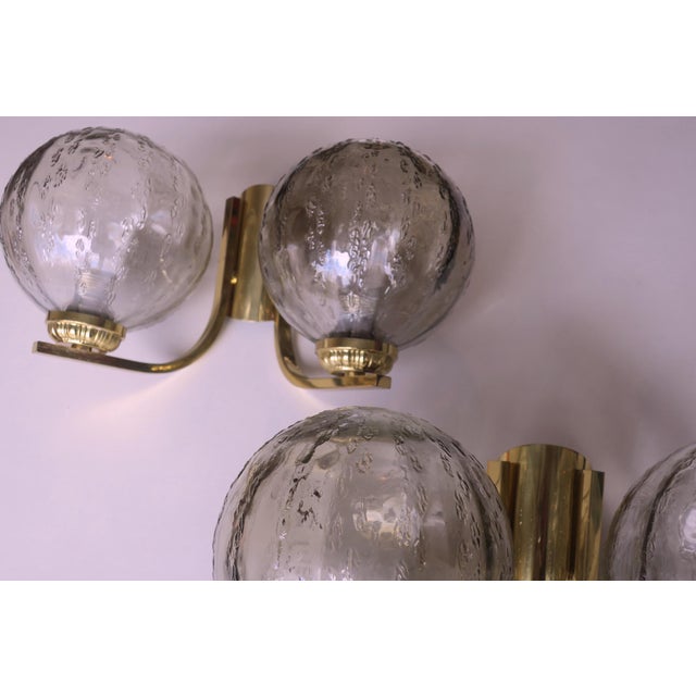 A pair of double wall lights from the 1970s, each with two globes in structured glass on a brass frame. Up to 250V...