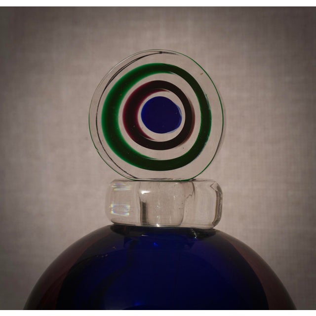 A perfume bottle with internal decorations in various shades of blue, green, and transparent. A sculpture of the highest...