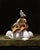 In "Test Results," a striking arrangement of animal skulls and white eggs emerges against a dark background, creating a...