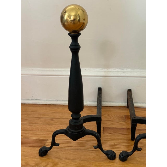 Beautiful American midcentury cast iron andirons with brass cannonball toppers. Heavy and solid. No maker's mark. Please...