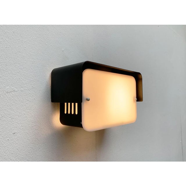 Minimalist mid-century wall light. Simple wall lamp in black and white. The luminaire body consists of a rectangular frame...