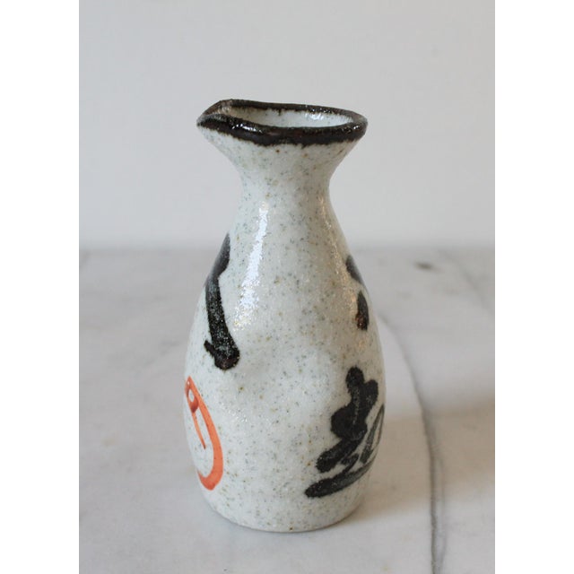 Vintage traditional Japanese tokkuri (sake decanter) crafted from speckled ceramic stoneware and decorated with rustic...