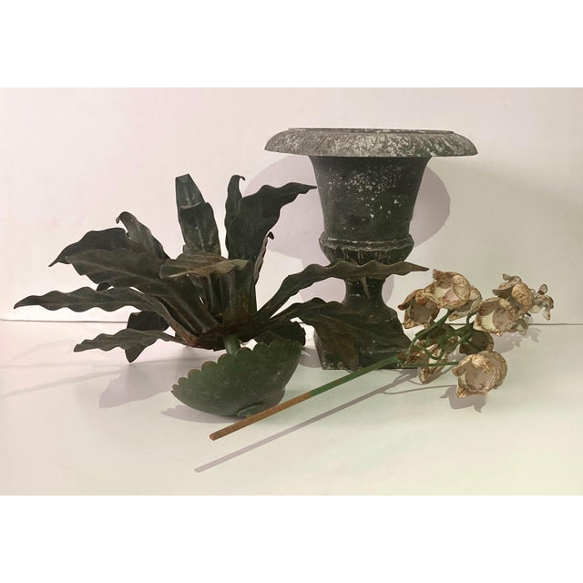 Hand wrought tole floral sculpture sitting tall in a Grecian charcoal gray heavy iron urn. Stem of chippy white bell...
