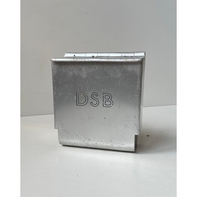 Wall ashtray with flip-lid built as a tank and used by DSB in Denmark during the 1970s. Logo to its front. It is made from...