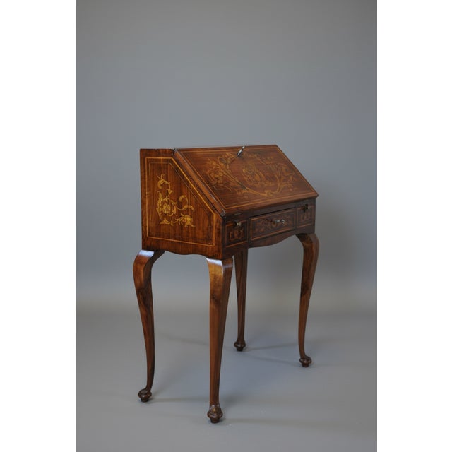 A small, freestanding writing desk from the late 19th/early 20th century, entirely inlaid with floral motifs and...