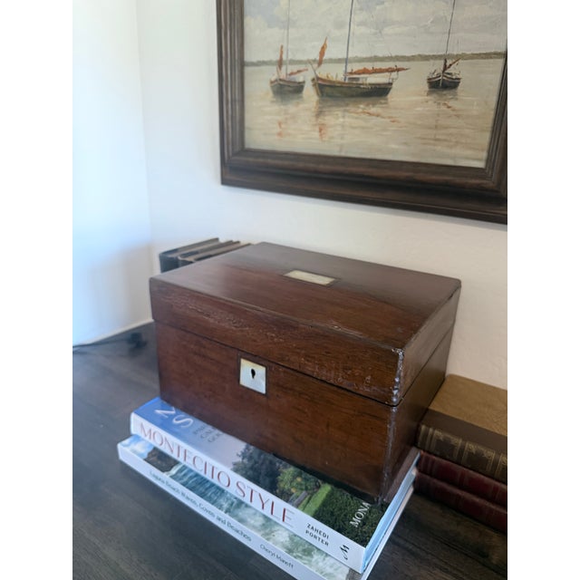 A handsome antique mahogany writing box featuring a rich aged patina, mother-of-pearl inlaid cartouche and escutcheon, and...