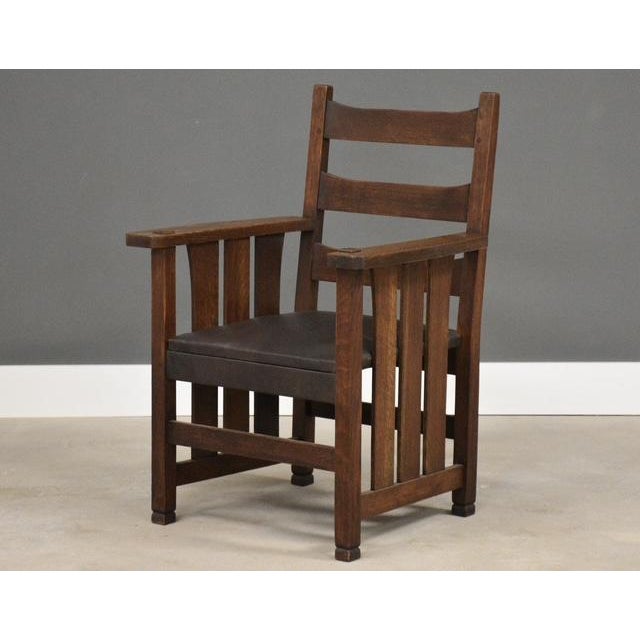 A rare L&JG Stickley Onondaga captain’s dining chair constructed of quarter sawn oak and a leather seat. Original finish....