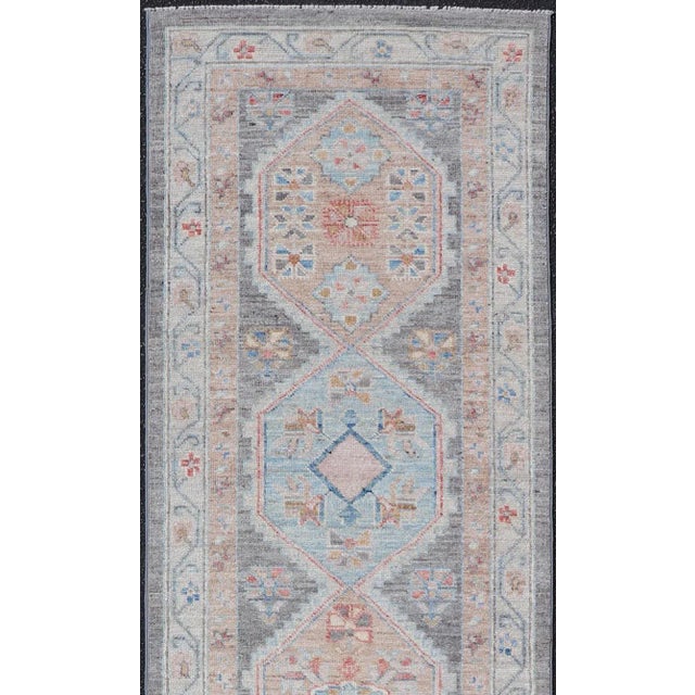 This Hand-Knotted Oushak presents a floral border on top of a dark gray background, accenting colors such as blue, red,...