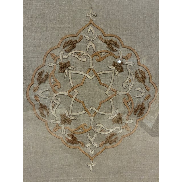 Handsome framed textile artwork by Trowbridge, featuring an elaborate symmetrical floral medallion embroidered on natural...