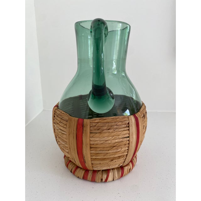 Beautiful vintage green blown glass pitcher featuring a rattan woven base. This could work for a bar cart, open shelves,...