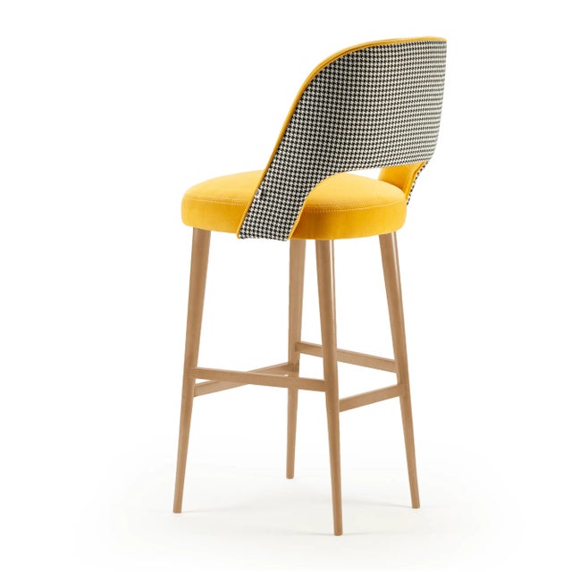 The Ava bar chair features a solid wood structure with polished brass fittings. The exterior fabric upholstery is in...