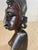 This sculpture is a bust of a woman, with its traditional hair cut. This is in wood, in a black color, and has been made...