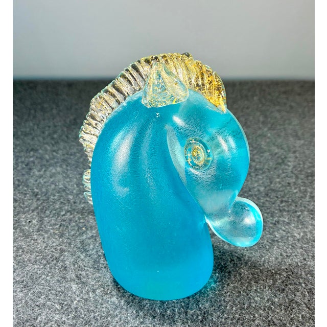 Art glass in the form of a decorative horse head in aqua blue with the ears and mane accented with clear glass and gold...