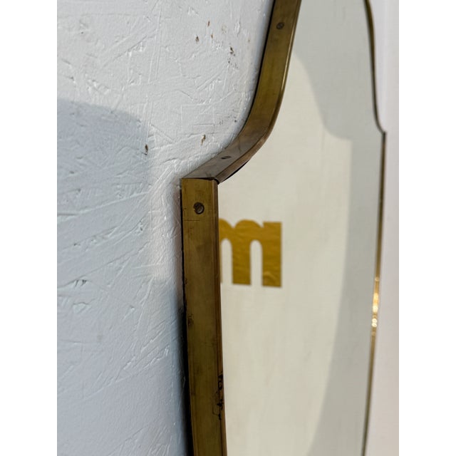 Italian shield-form mirror from the 1950s, framed in a delicate brass border that enhances their elegant silhouettes. The...