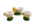 A charming set of three Bordallo Pinheiro ceramic egg cups modeled as yellow chicks perched on green grassy bases. Each...