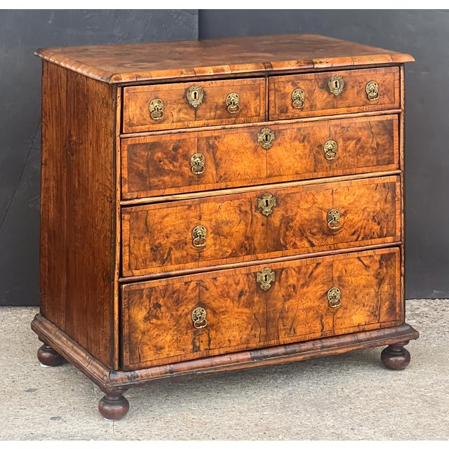 A fine English chest of drawers of walnut and oak from the Queen Anne period, circa 1710, featuring a moulded top of...