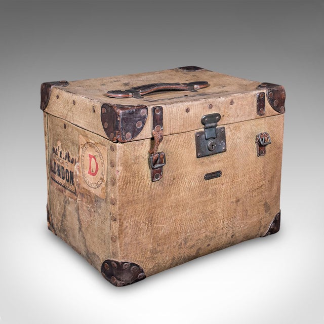 This is an antique travel trunk. An English, canvas and leather gentleman's voyage case with a pair of engraved tankards...
