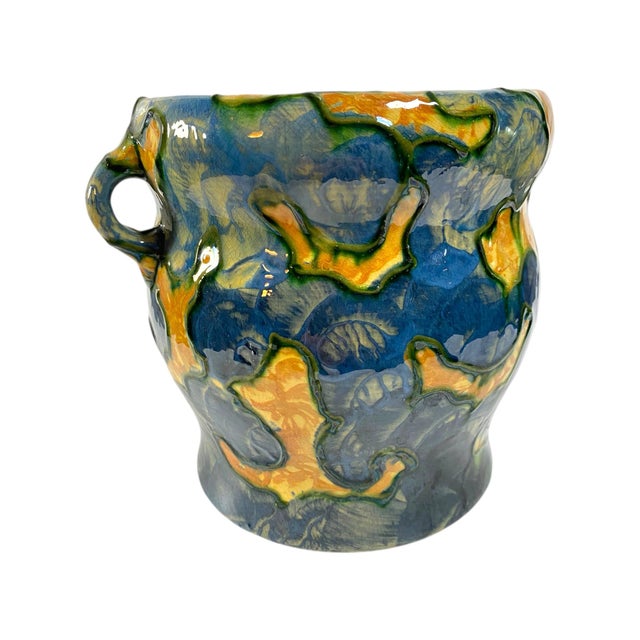 A ceramic jardiniere with foliage design in green and blue on a gold ground. Double handles, signed on bottom Michael...
