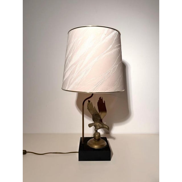 A striking vintage table lamp featuring a beautifully detailed eagle with outstretched wings, perched on a sphere and...