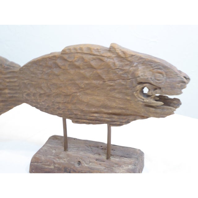 This rustic carved wooden fish is mounted on a block of wood.