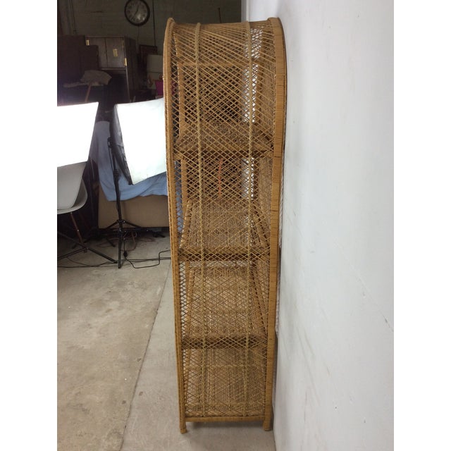 This vintage boho chic shelving unit features rattan construction with original finish, four shelves, and arched top.