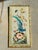 A beautifully framed embroidered textile artwork featuring a vibrant blue exotic bird perched among delicate blossoms and...