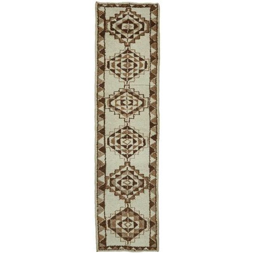 This exquisite runner rug is a rare example of tribal craftsmanship, hand-knotted by the women of the Herki tribe during...